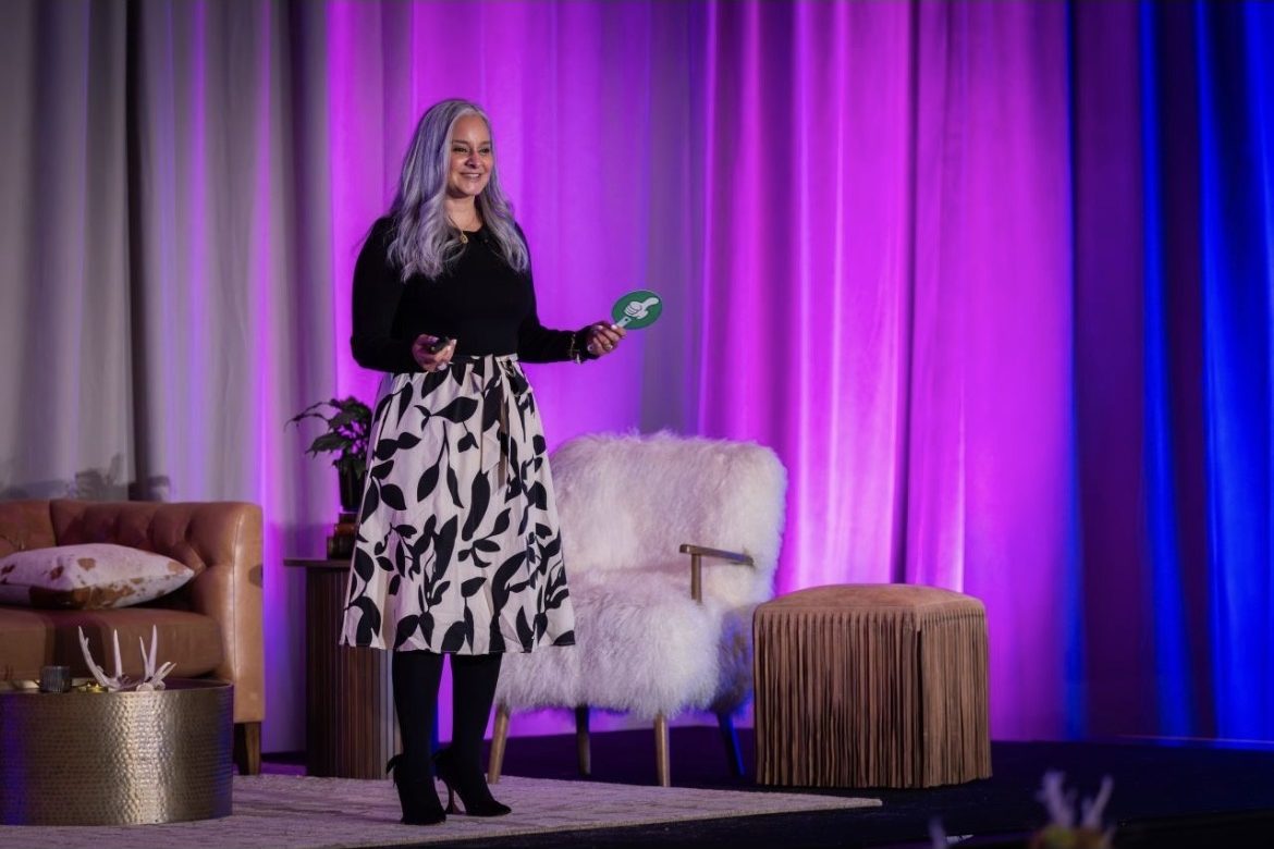 Dalia presenting on a stage lit in purple and blue