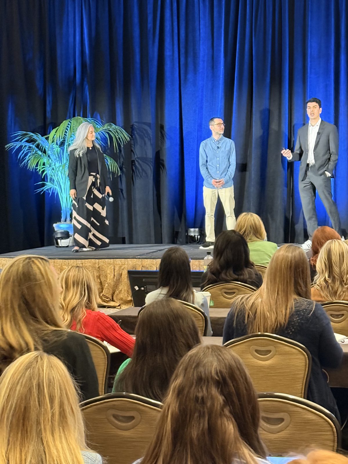 Dalia on stage at AIM with two other speakers in front of a seated audience